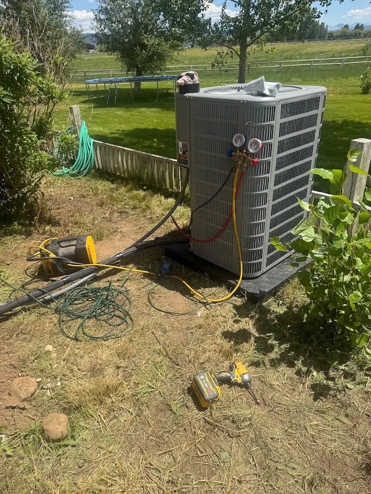 Residential air conditioner condenser being serviced with manifold gauges