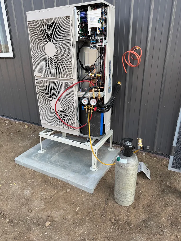Air-to-water heat pump installed on a concrete pad with gauges connected