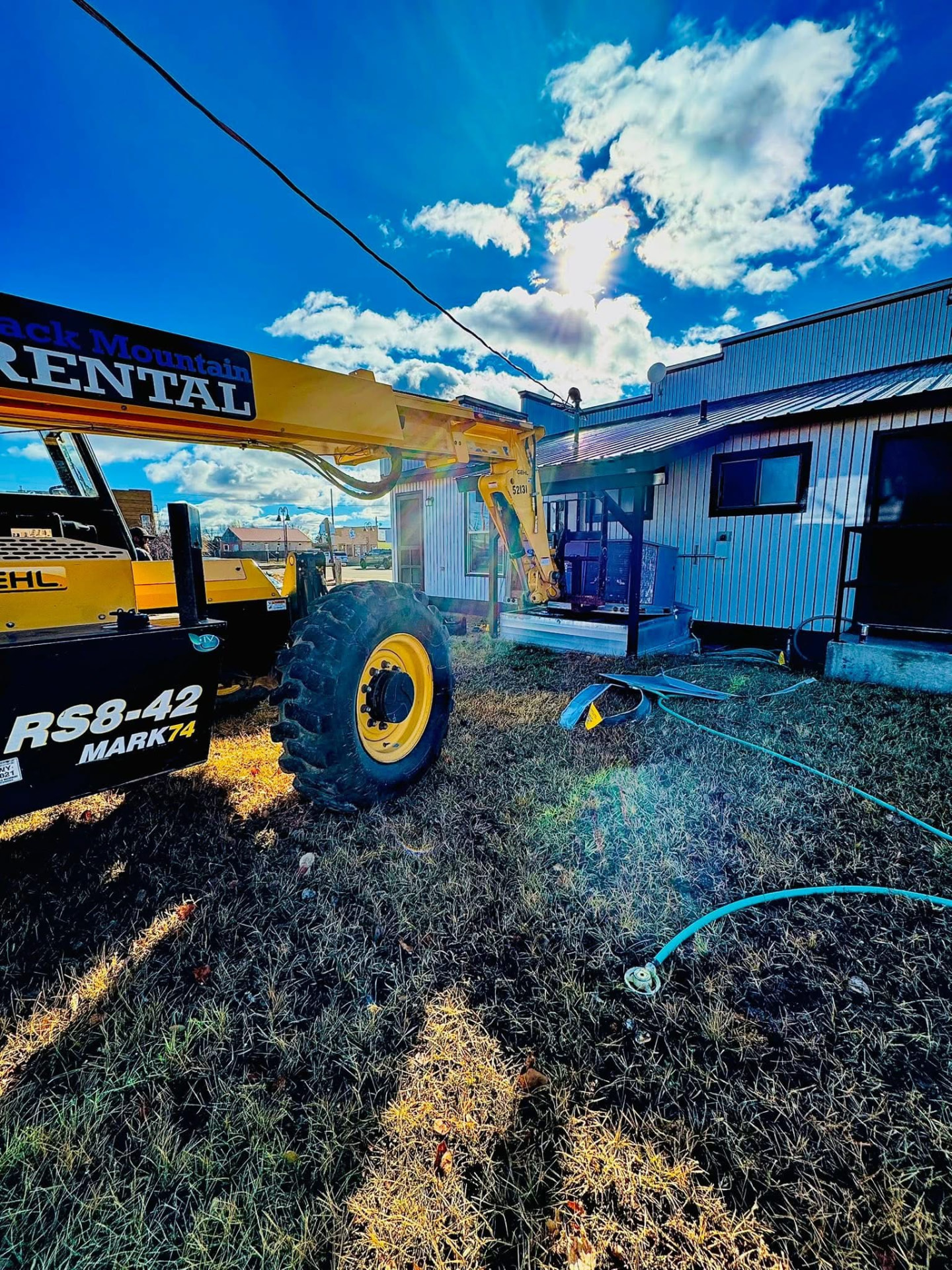 Telehandler positioned beside a building to lift equipment onto the roof